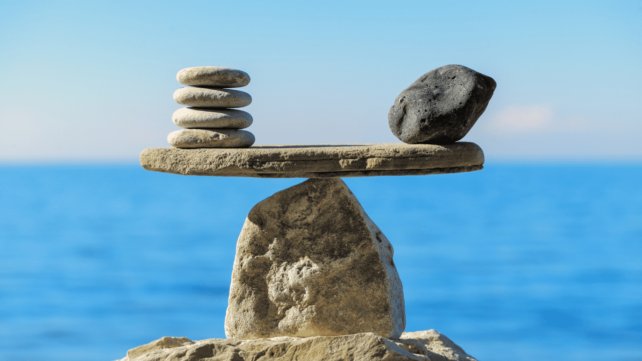 Balanced stones on a seesaw, symbolizing equilibrium.